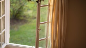 A window with a view of greenery outside. - Spacious 6-bedroom house in  Varennes, pool, 3 outdoor spaces, full gym, bikes. (Varennes)
