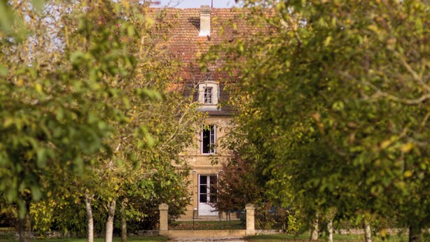 A pathway leading to a building with a traditional architectural style, surrounded by trees and a clear sky. - Spacious 6-bedroom house in  Varennes, pool, 3 outdoor spaces, full gym, bikes. (Varennes)