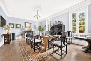 A dining room with a wooden table, chairs, and a patterned rug.