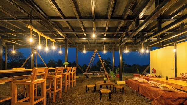 Un espacio al aire libre con mobiliario de madera, una hamaca y vistas al cielo.