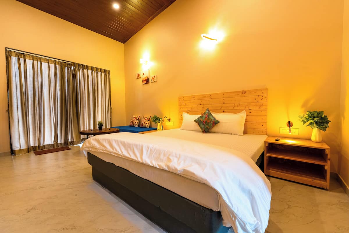 Un dormitorio con una cama grande, cabecera de madera, mesitas de noche y vistas a un balcón con cortinas.