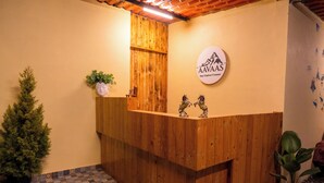 Un mostrador de recepción de madera con un logotipo, una pequeña estatua y una planta en maceta.