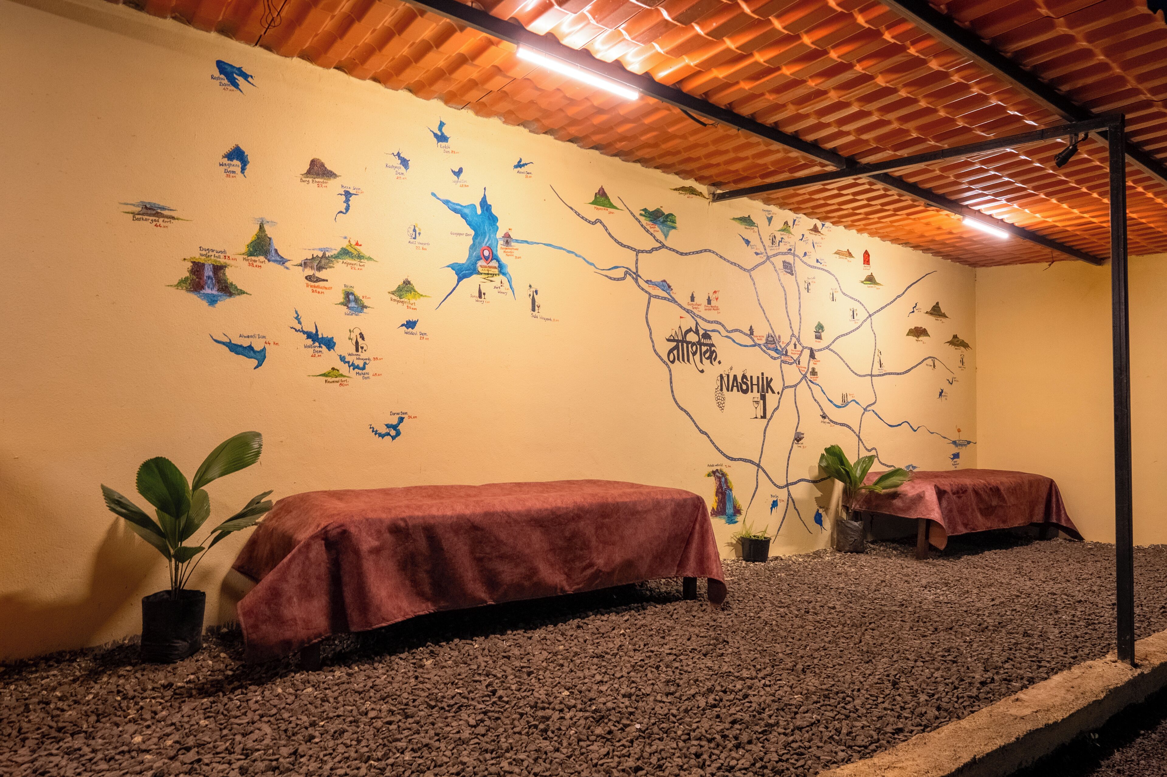 A room with a map mural, two beds with red covers, and a tiled ceiling.