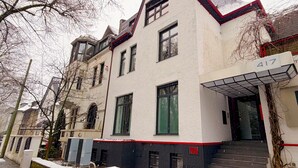 Een meerhoog gebouw met een witte gevel, zwarte accenten en een rood dak.