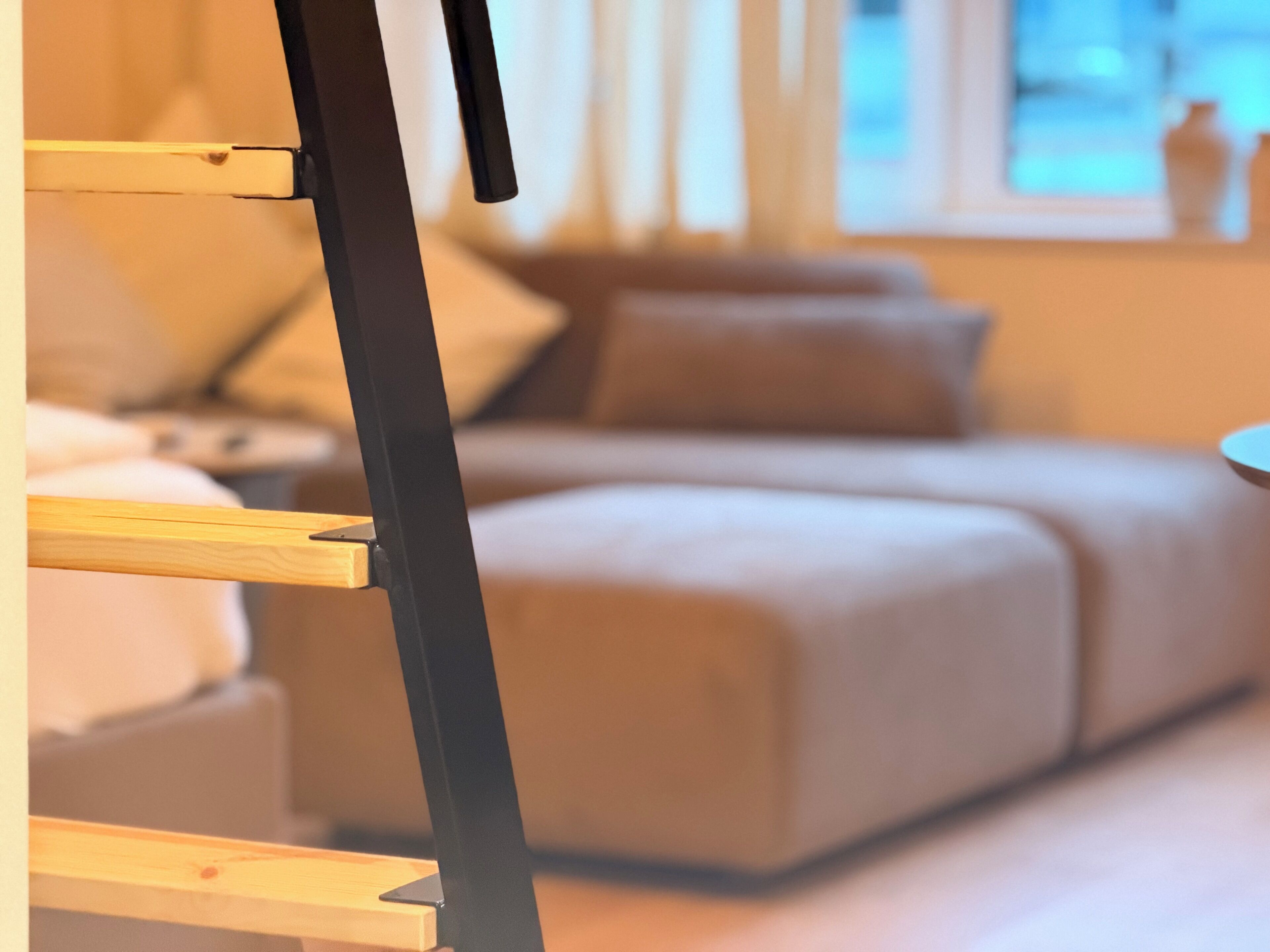 Een moderne woonkamer met een bank, een bijzettafeltje en een zwarte verticale constructie.