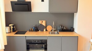 Een moderne keuken met een ingebouwde oven, een koffiezetapparaat en een messenblok.