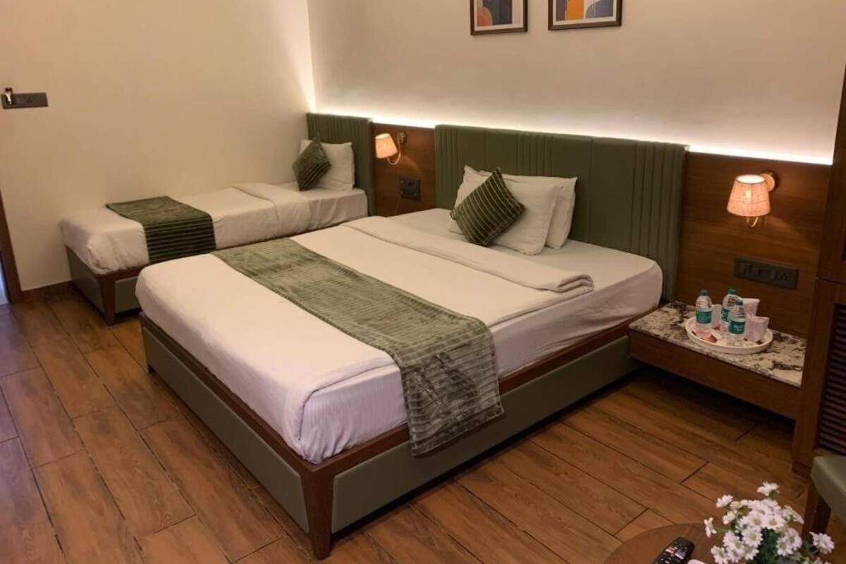 Habitación de hotel con dos camas, una mesita de noche con lámpara y una peque ña mesa con artículos de aseo.