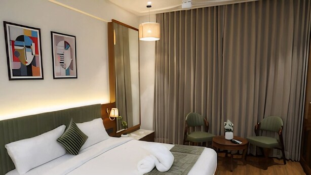 Ein Hotelzimmer mit einem Bett, zwei Stühlen, einem Tisch, einem Spiegel und Bildern an der Wand.