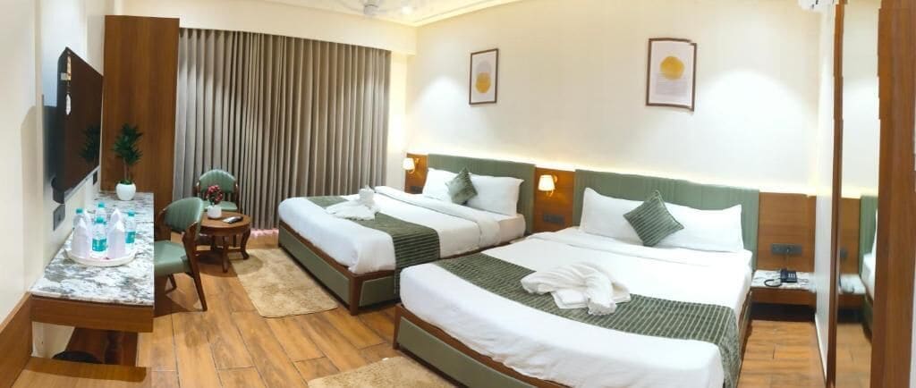 A hotel room with two beds, a desk with a chair, a TV, and a window with curtains.