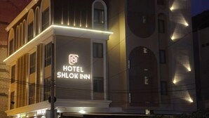 Ein Gebäude mit einer auffälligen Schild, auf dem 'HOTEL SHLOK INN' steht und einem Logo darüber.