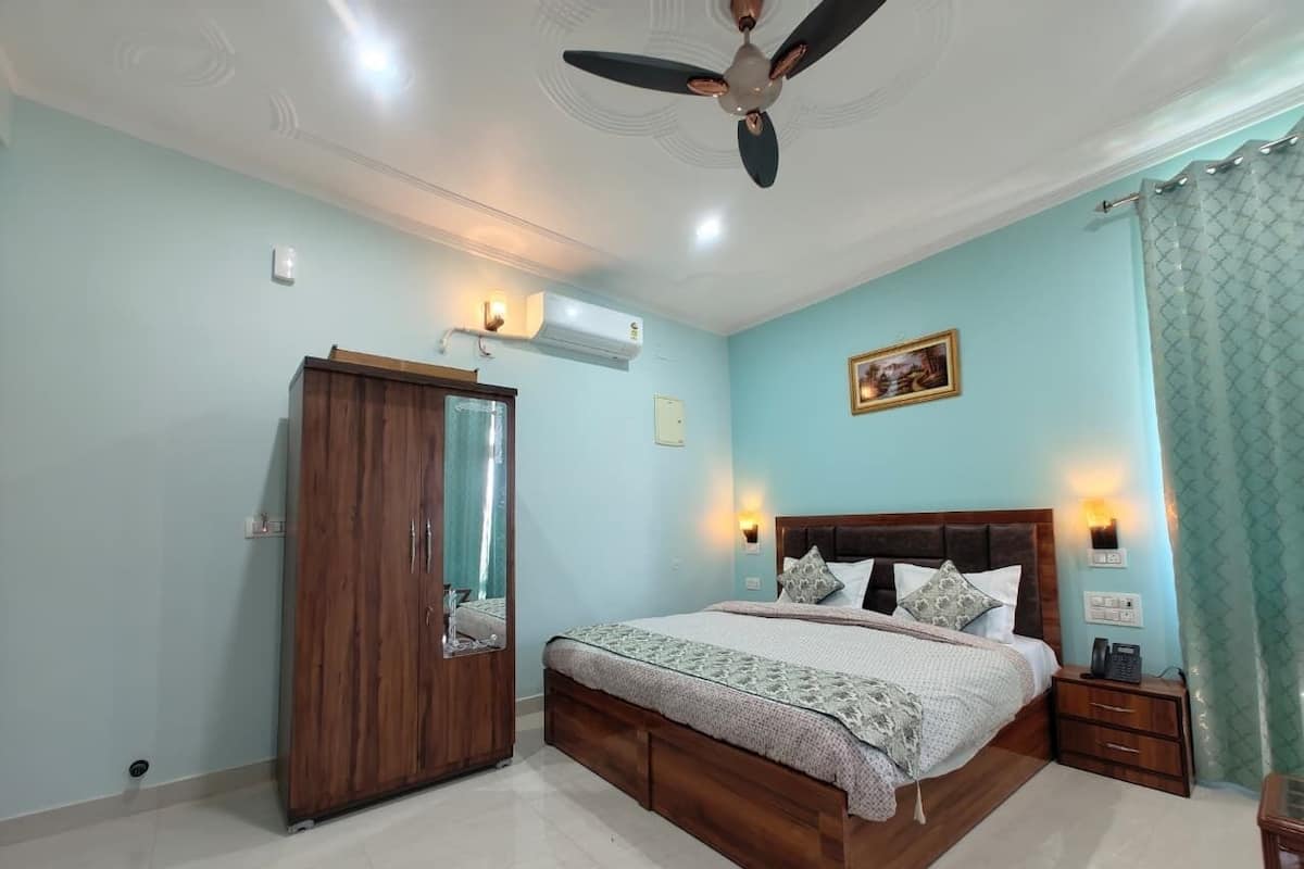 A bedroom with a bed, a wardrobe, a ceiling fan, an air conditioning unit, a bedside table, and a nightstand.