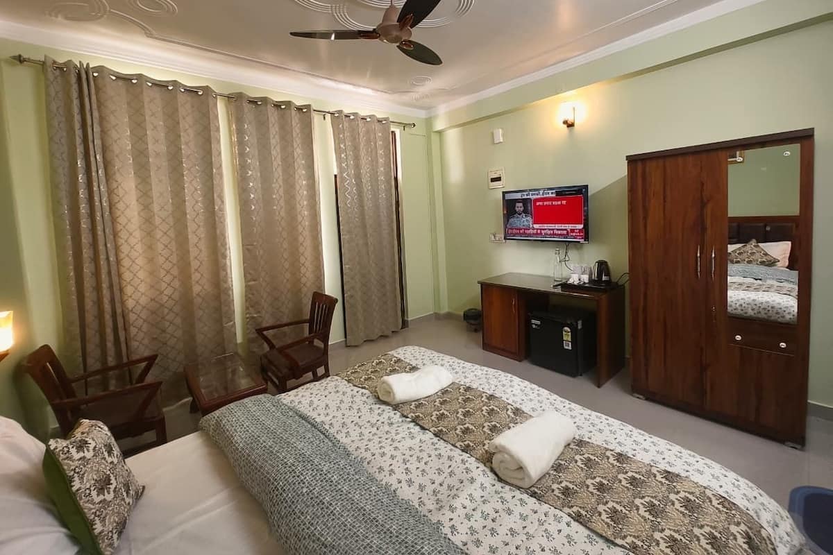 A hotel room with a bed, a desk, a chair, a television, and a wardrobe.