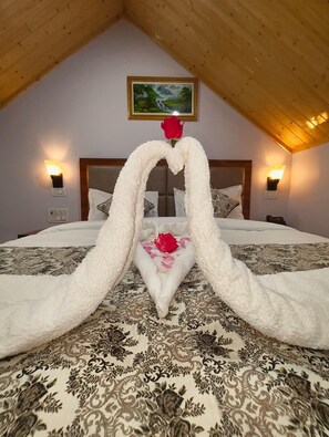 A bedroom with a bed, a heart-shaped towel arrangement, a single red rose, and a painting on the wall. - AASRA PARADISE HOTEL (Dharamshala)