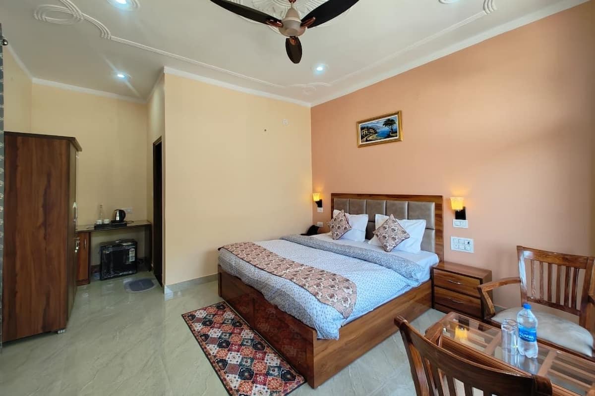 A bedroom with a bed, a ceiling fan, a nightstand, a chair, and a small table with a bottle.