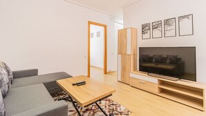 Una sala de estar moderna con sofá, mesa de centro, televisor y mueble.