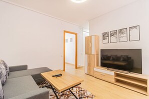 A modern living room with a sofa, a coffee table, a TV, and a cabinet.