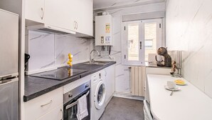 Una cocina compacta con lavadora, un lavamanos y una ventana.