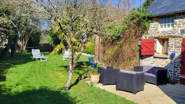 Een stenen huis met een terras, zitplaatsen buiten en een tuin.