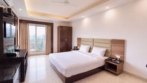 Quarto de hotel com cama, mesas de cabeceira, escrivaninha com televisão e guarda-roupa.
