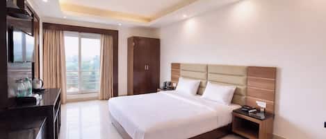 A hotel room with a bed, bedside tables, a desk with a TV, and a wardrobe.