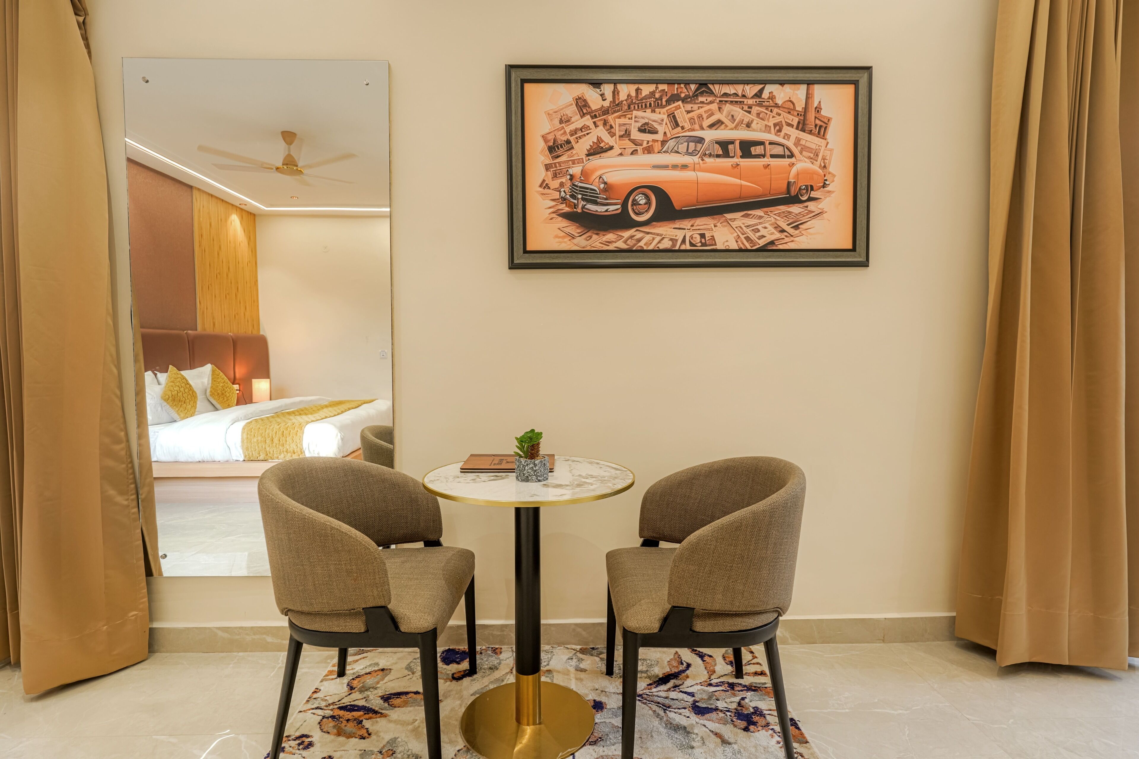 A hotel room with a bed, a round table with two chairs, a framed picture on the wall, and a view through a window.
