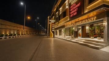 A hotel with a well-lit entrance, a visible restaurant, and a clear pathway leading to the entrance.