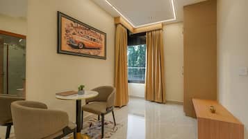 A modern living room with a dining area, a large window with curtains, and a framed picture on the wall.