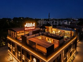 Un bar restaurante de varios pisos con un letrero iluminado llamativo, mesas al aire libre y vistas del paisaje urbano circundante.