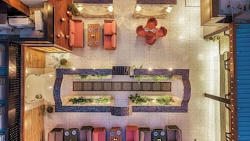 Un vestíbulo de hotel con una zona de estar central, una recepción y una pared decorativa con plantas.