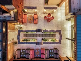 Un vestíbulo de hotel con una zona de estar central, una recepción y una pared decorativa con plantas.