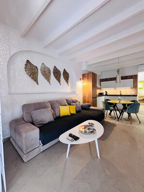 Een moderne woonkamer met een bank, een salontafel en een eethoek met stoelen en een tafel.