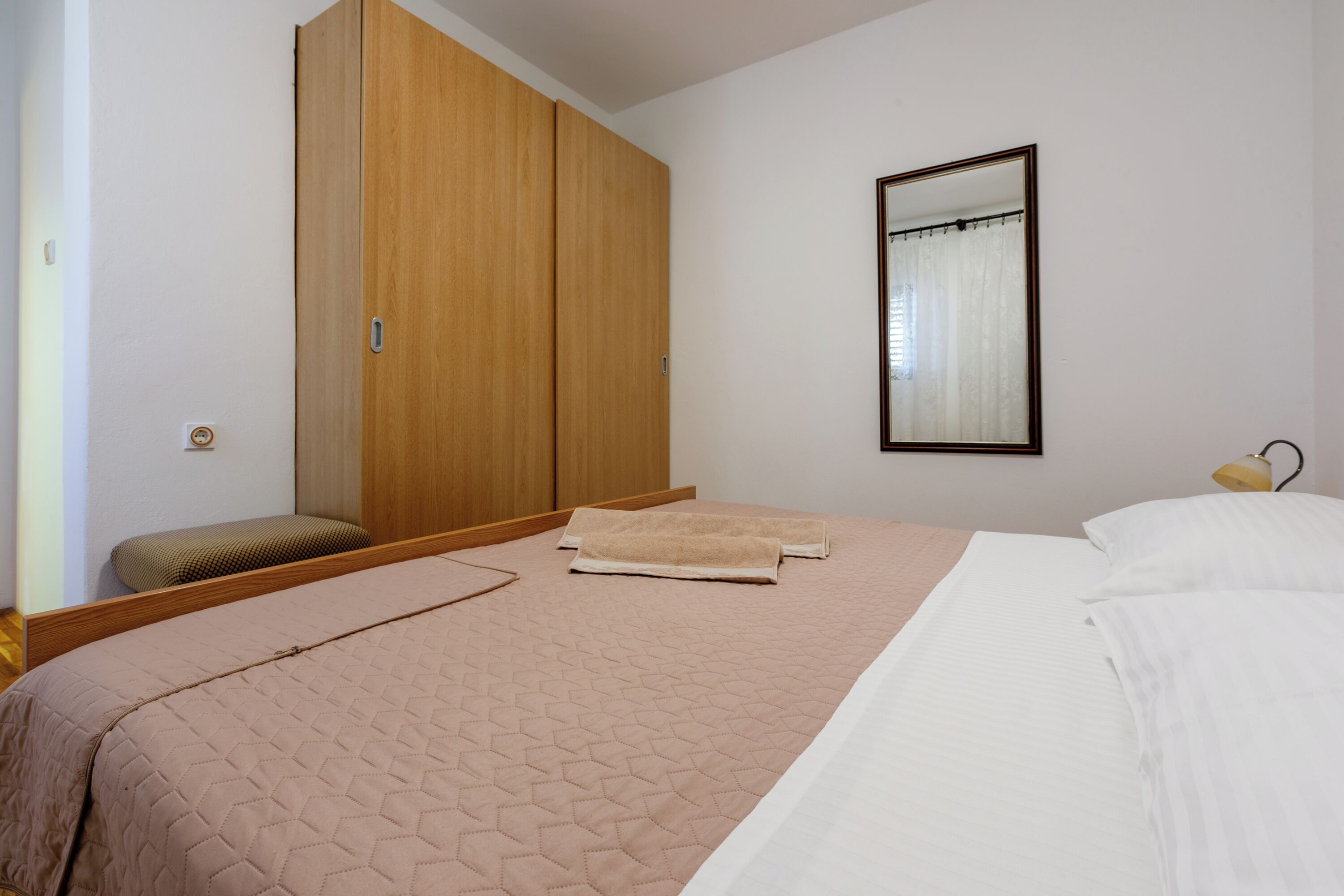 Une chambre à coucher avec un lit, une armoire en bois, un miroir et une lampe de chevet.