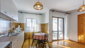 Une cuisine avec un coin repas, un plancher en bois et une grande fenêtre.