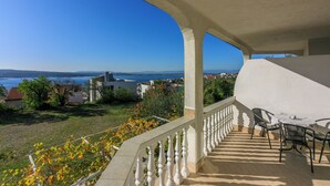 Un balcon avec vue sur la mer, une balustrade blanche et une table avec des chaises.