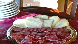 Une assiette de charcuteries et de fromages coupés, posée sur une table recouverte d’une nappe à motifs.