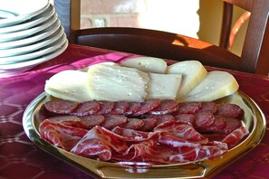 A plate of sliced meats and cheeses on a table with a patterned tablecloth. - Apartment in Montefortino With Communal Pool (Montefortino)