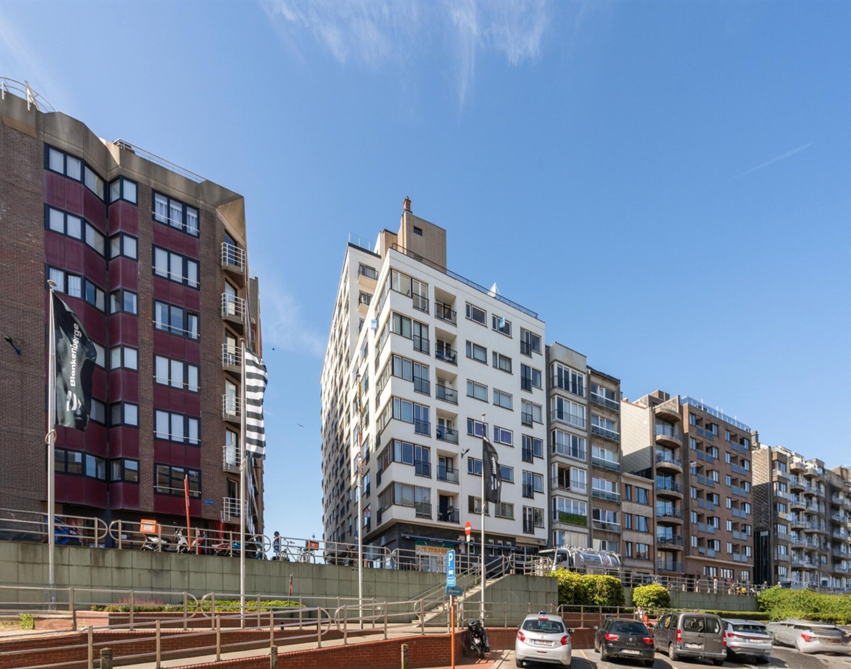 Un edificio residencial de varios pisos con un diseño arquitectónico moderno, con balcones y fachada de ladrillo.