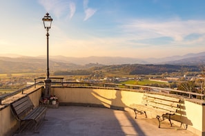 Un balcone con una panchina, un lampione e vista sulla valle.