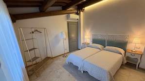 Een slaapkamer met een bed, twee nachtkastjes met lampen, een kledingkast en een kledingrek.