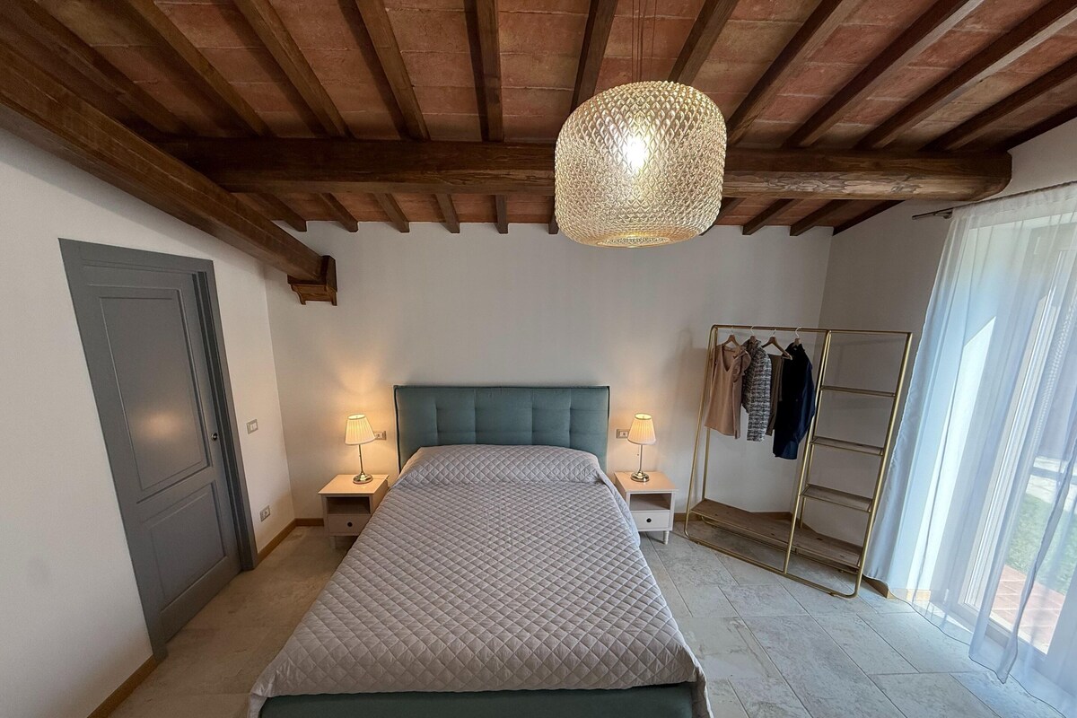 Ein Schlafzimmer mit einem Bett, zwei Nachttischen mit Lampen, einem Kleiderschrank und einer Pendelleuchte.