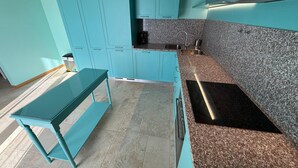 Een keuken met blauwgroene kastjes, een granieten aanrechtblad en een roestvrijstalen spoelbak.