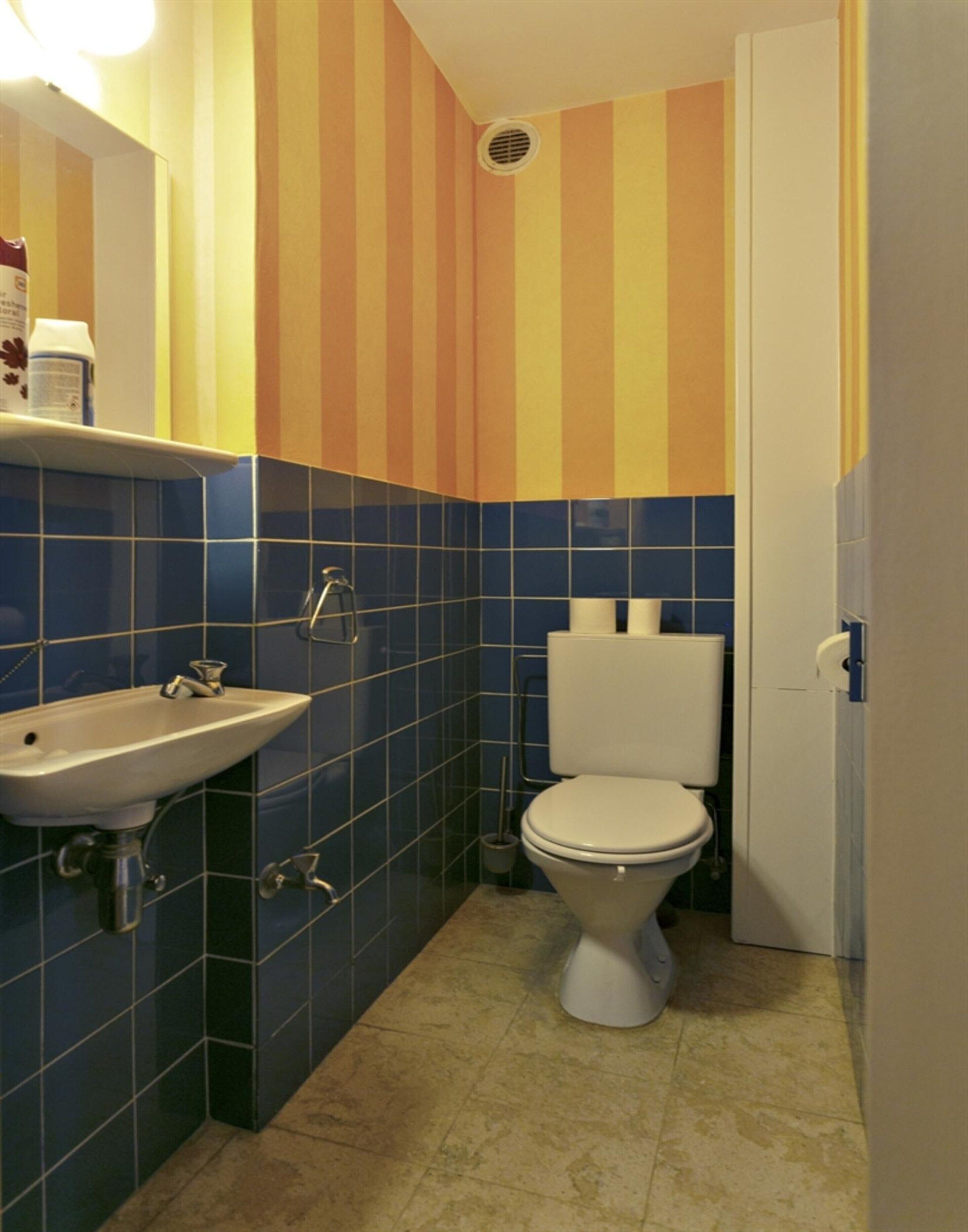 Un baño con lavamanos, inodoro y paredes a rayas.