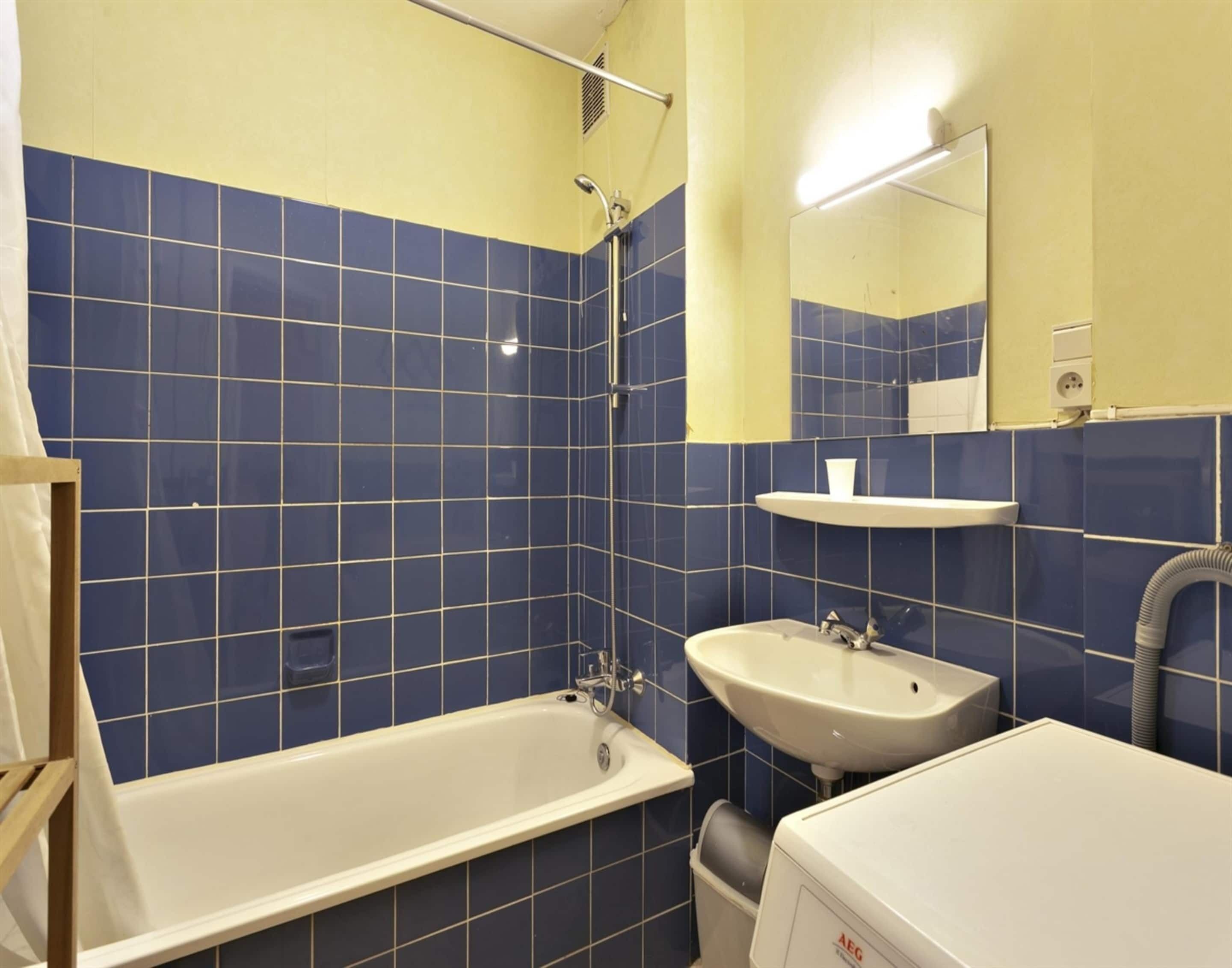 A bathroom with a bathtub, a sink, and a mirror.