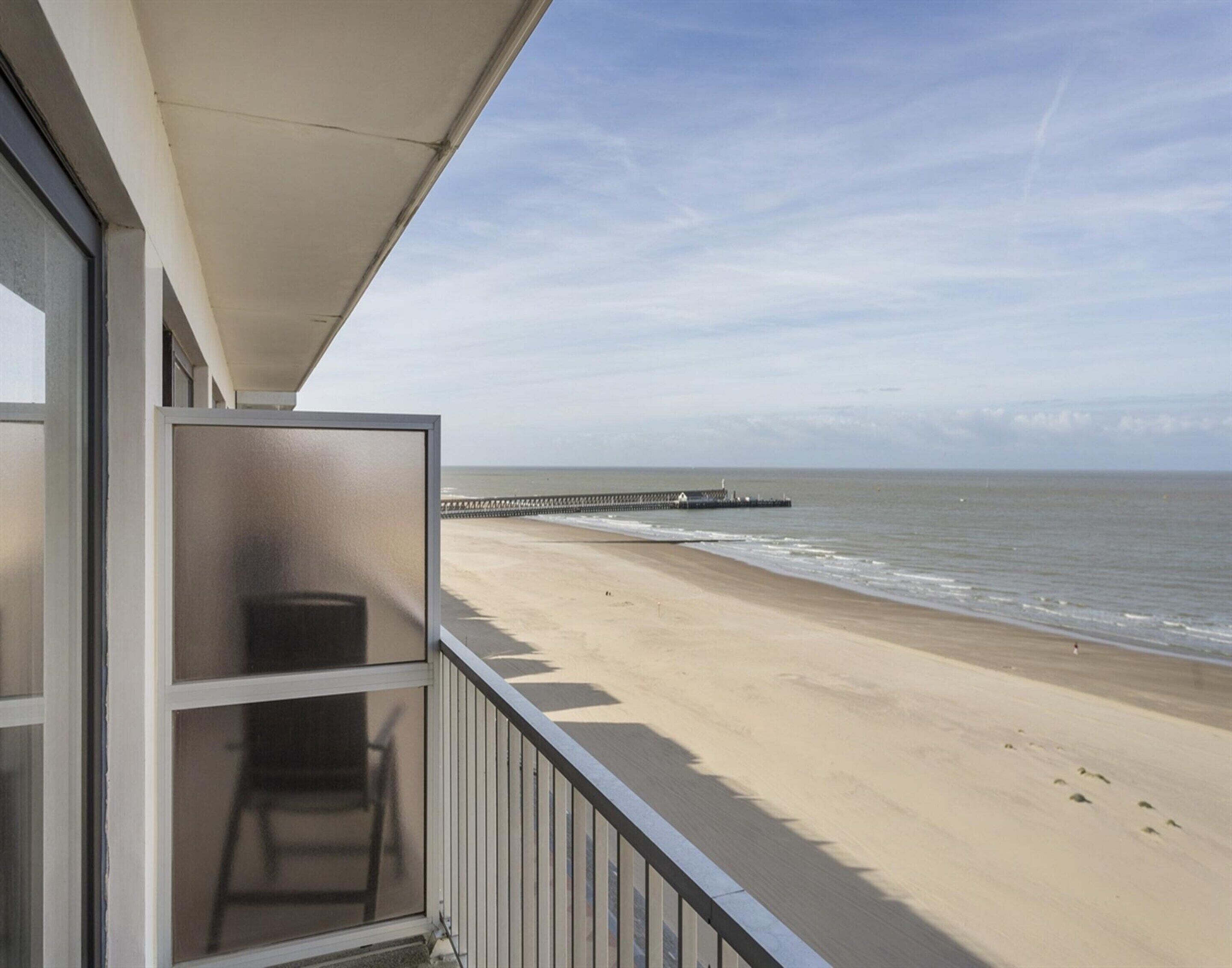 A balcony with a view of a beach and a pier.