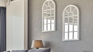 Un salón moderno con un sofá gris, un radiador blanco y dos apliques de pared de arco.
