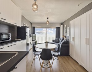 Eine moderne Küche mit Essbereich, Fernseher und einem Balkon mit Aussicht.