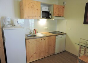 A compact kitchen with wooden cabinets, a microwave, a sink, a coffee maker, and a dishwasher. - Apartment Near Centre of Orelle (Orelle)