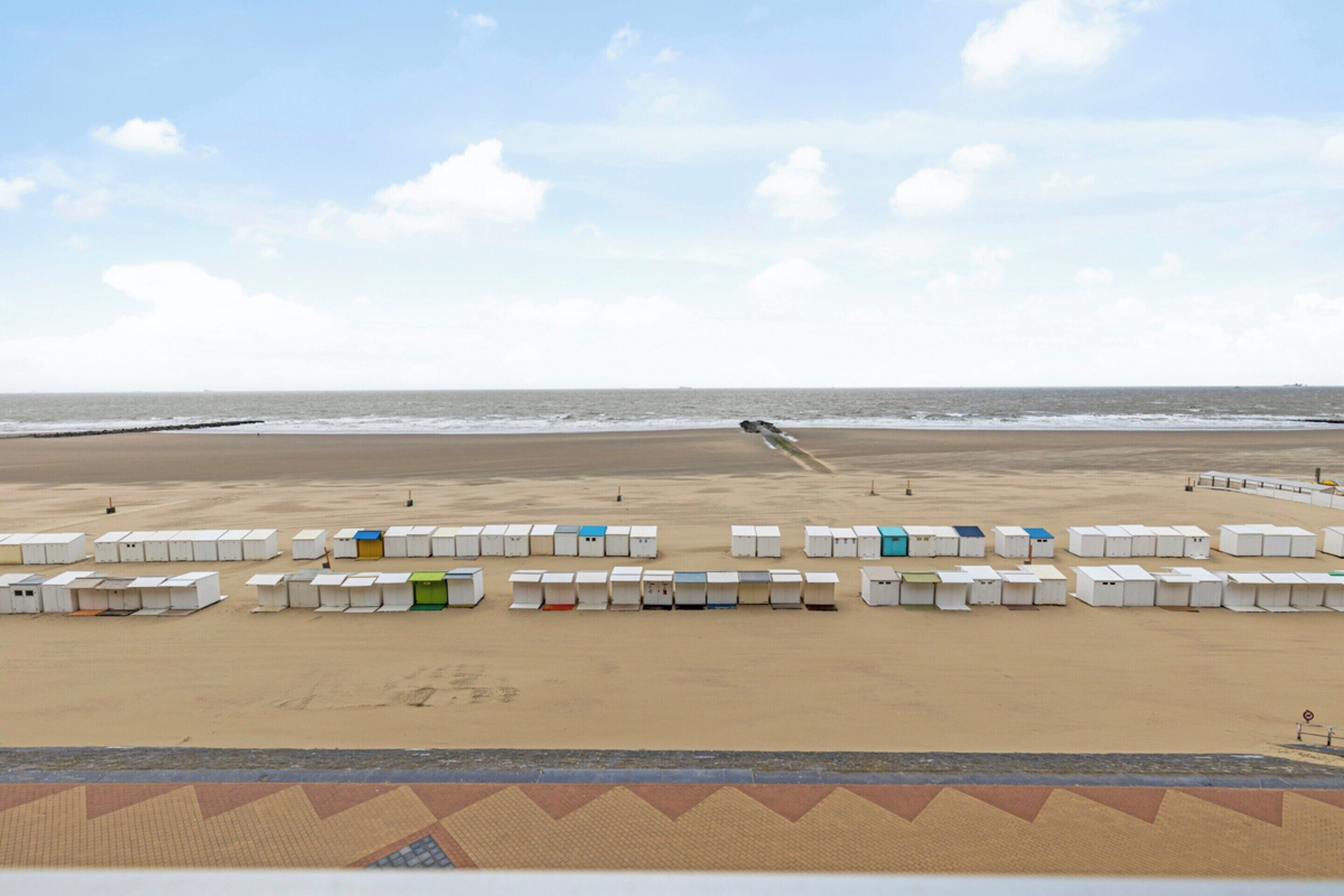 A beach with rows of white and colored beach huts.