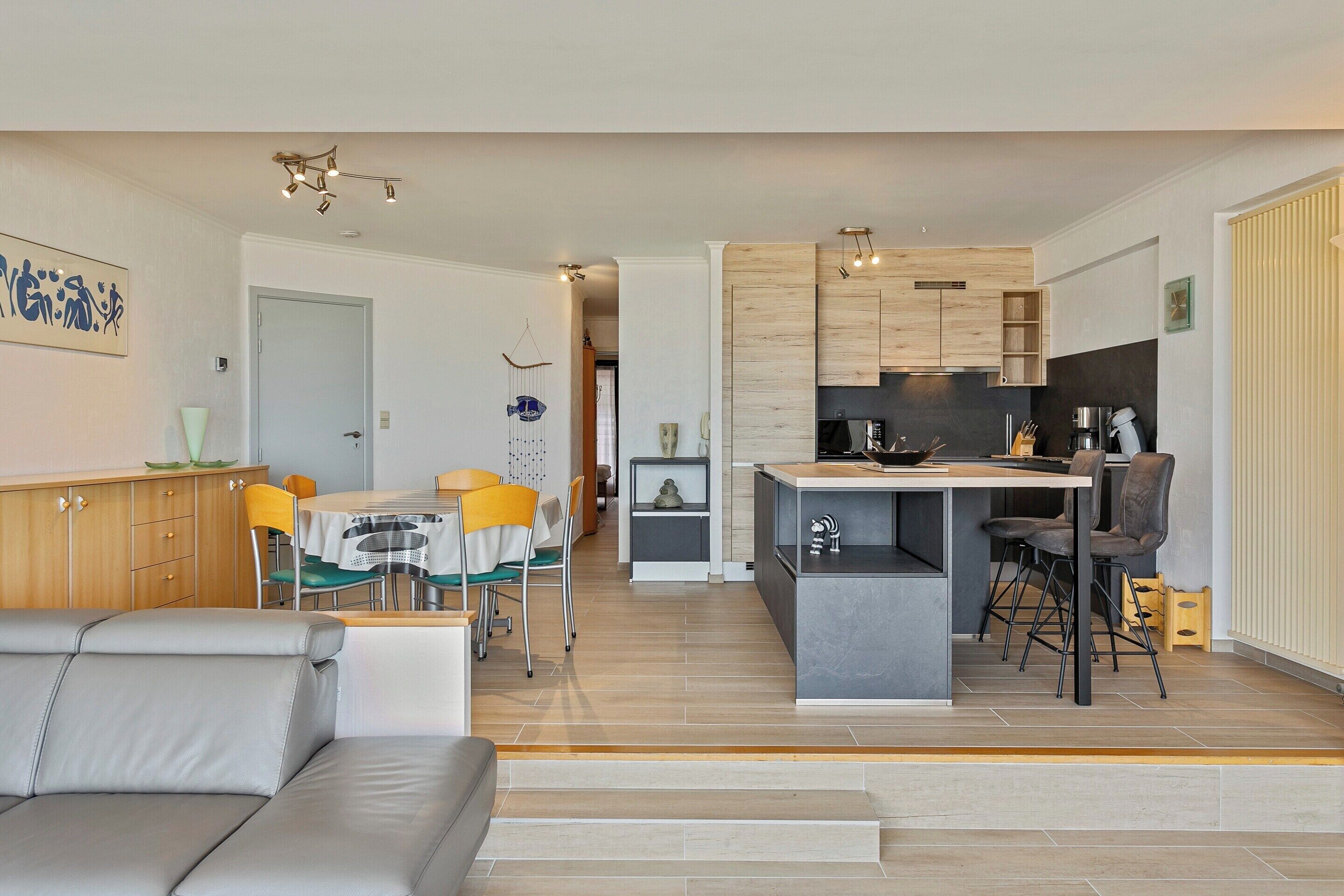 A modern kitchen with a central island, wooden cabinets, and a dining area with a table and chairs.