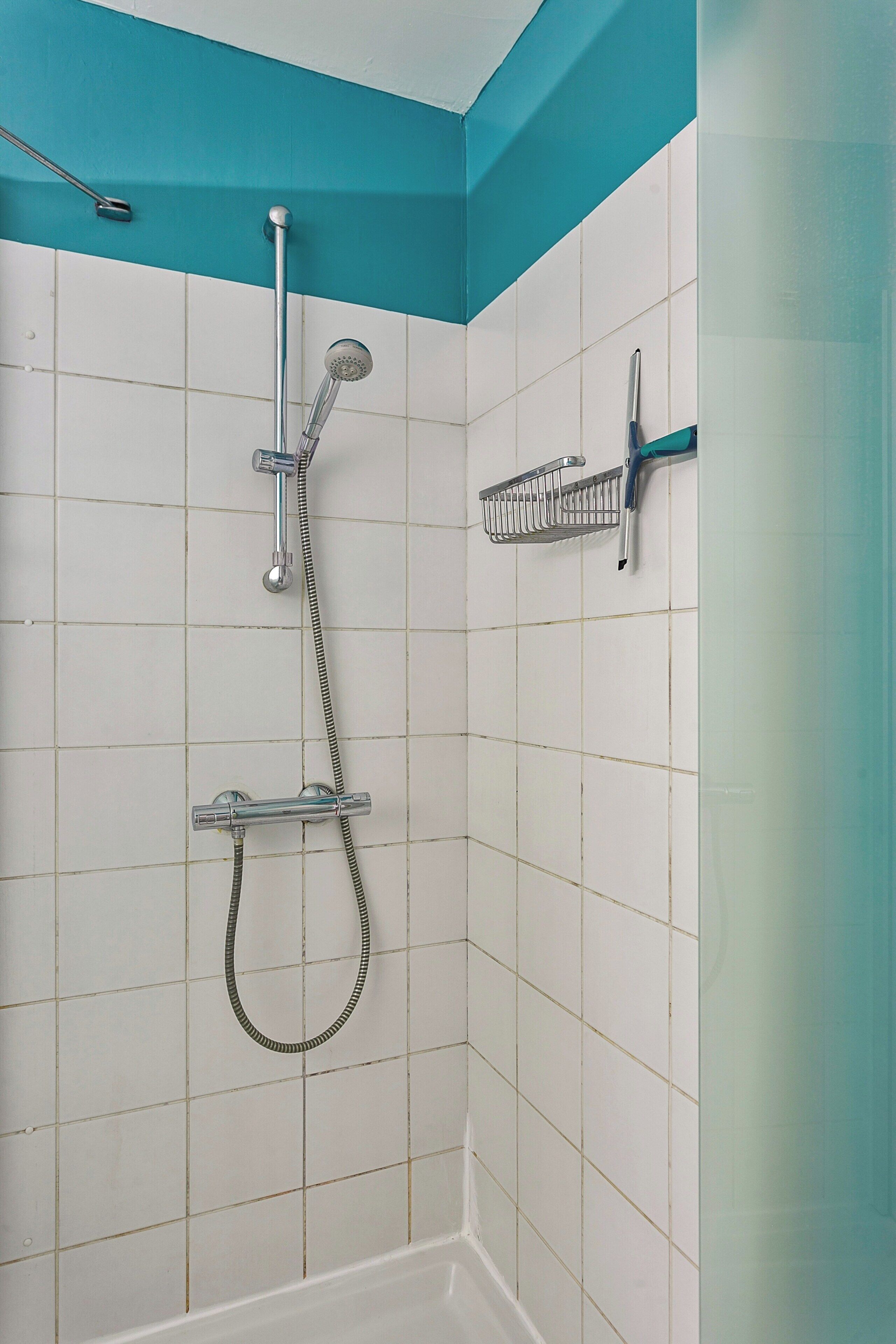 A shower with a handheld showerhead, a wall-mounted showerhead, and a handheld shower hose.
